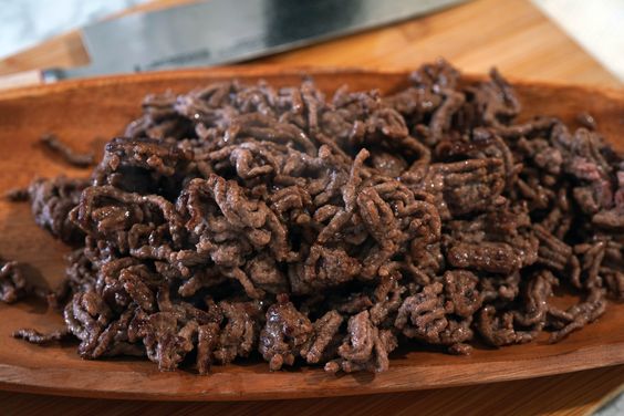 Carne molida dorada mezclada con salsa de tomate y ají panca para Tallarines Rojos
