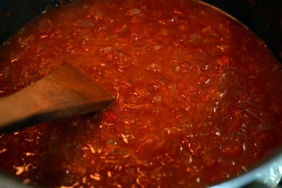 Salsa roja peruana cocinando a fuego lento con tomate y ají panca para Tallarines Rojos