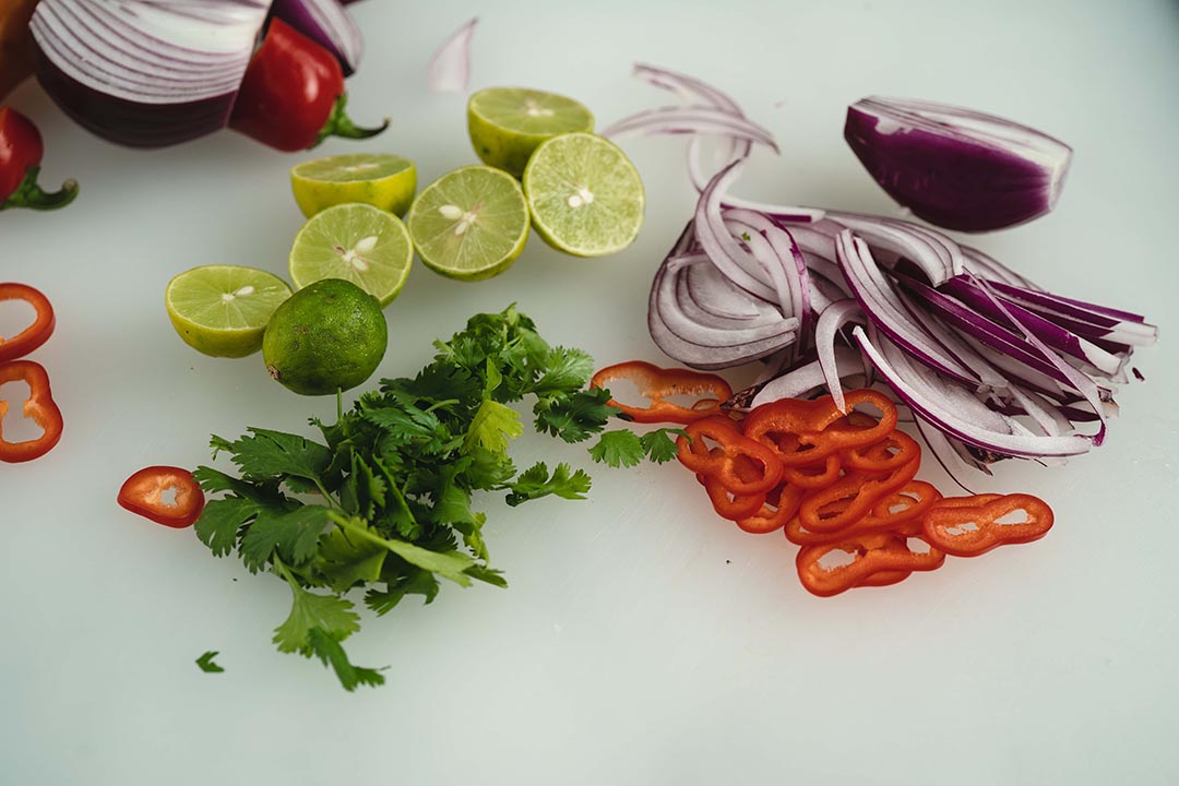 cilantro, lemons, peppers, onions on a board