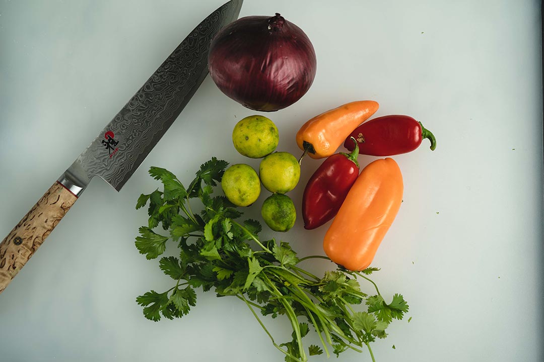 cilantro, lemons, peppers, onions on a board