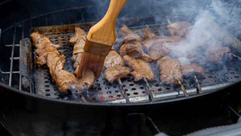 anticuchos on grill - Peruvian beef heart skewers cooking over high heat with panca glaze