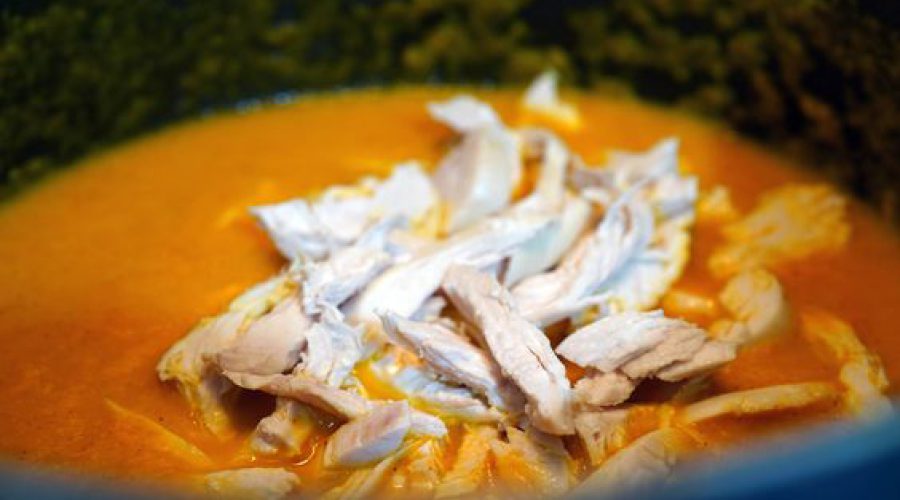 Shredded chicken being added to the sauce