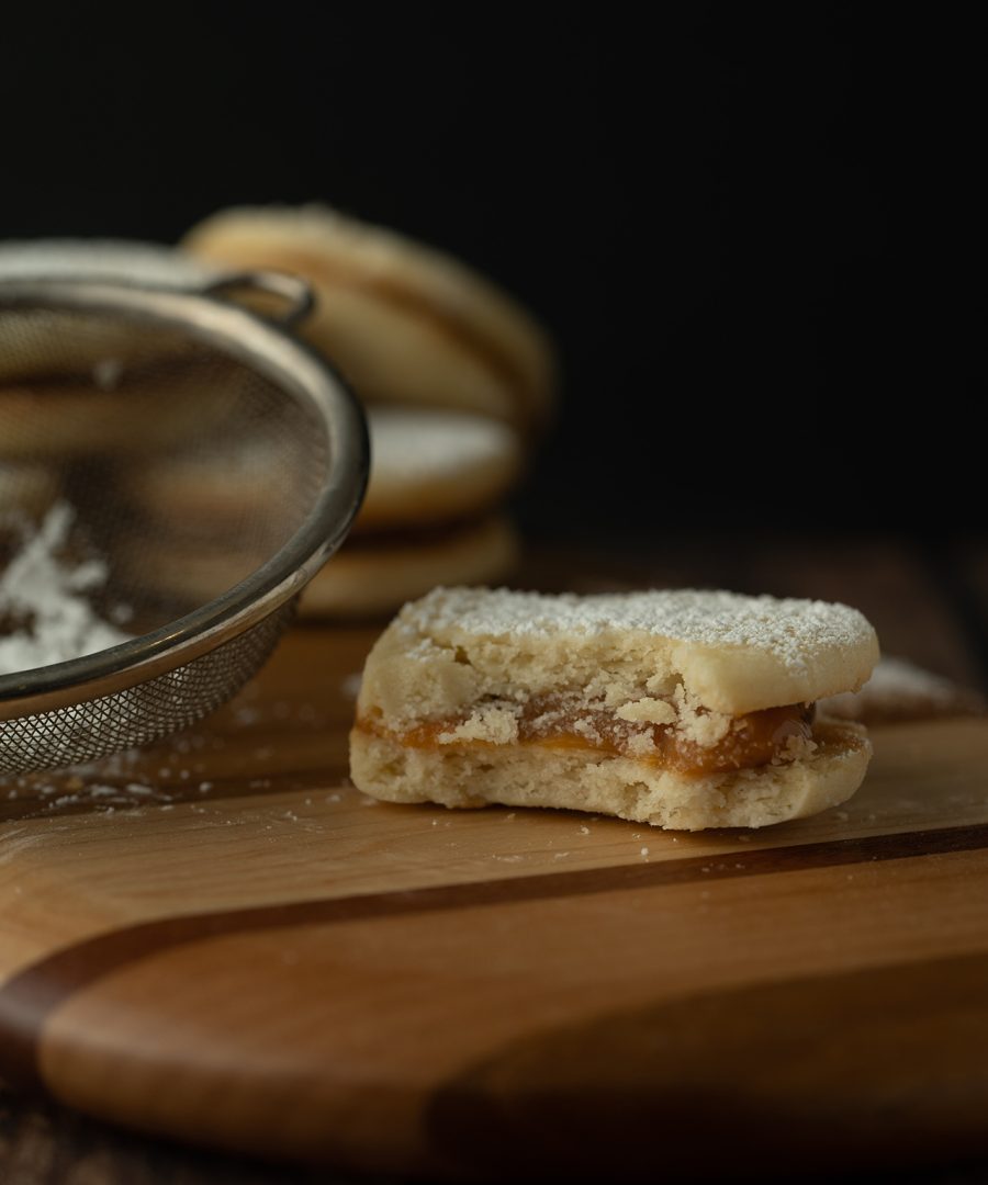 alfajores peruanos con dulce de leche y azucar en polvo - peruvian alfajores with dulce de leche and powdered sugar on wooden board