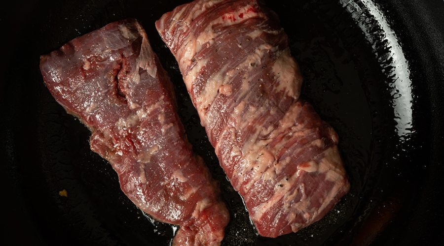 bistec peruano sellándose en sarten caliente - peruvian beef steak searing in hot pan