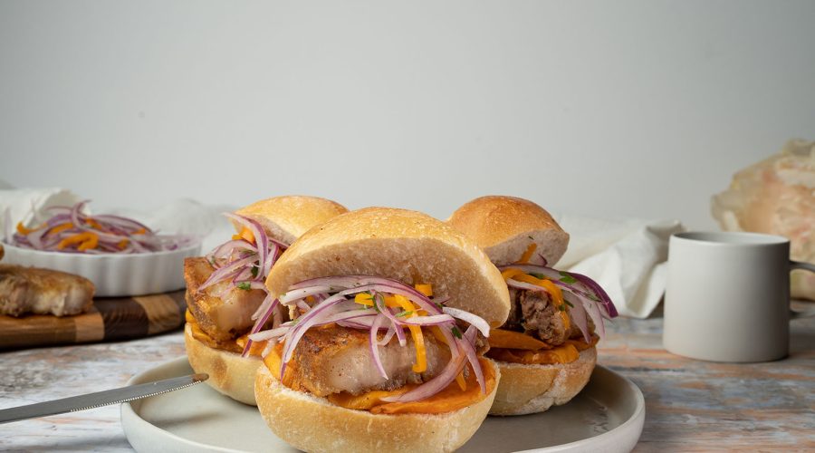 Peruvian pan con chicharrón with pork belly, sweet potato, and salsa criolla
