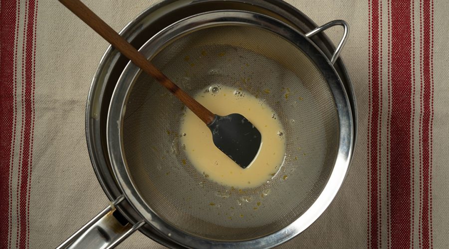 mezcla de crema volteada siendo colada para textura suave - crema volteada batter being strained for smooth texture