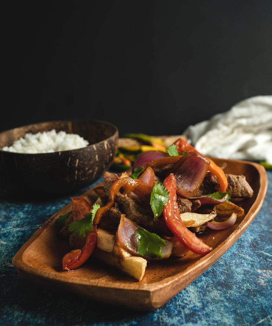 Lomo Saltado peruano auténtico servido en bowl de madera con arroz blanco al lado