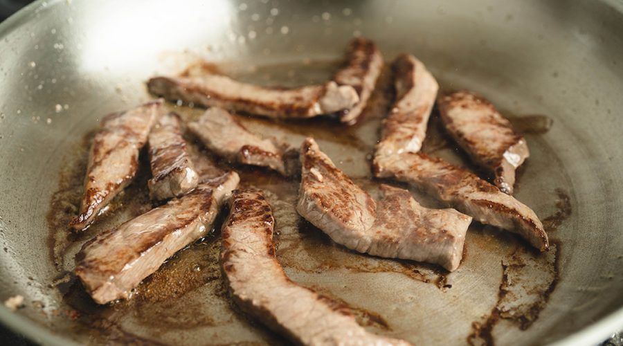 arne de res sellándose en sarten caliente para lomo saltado - sirloin strips searing in hot pan for peruvian lomo saltado