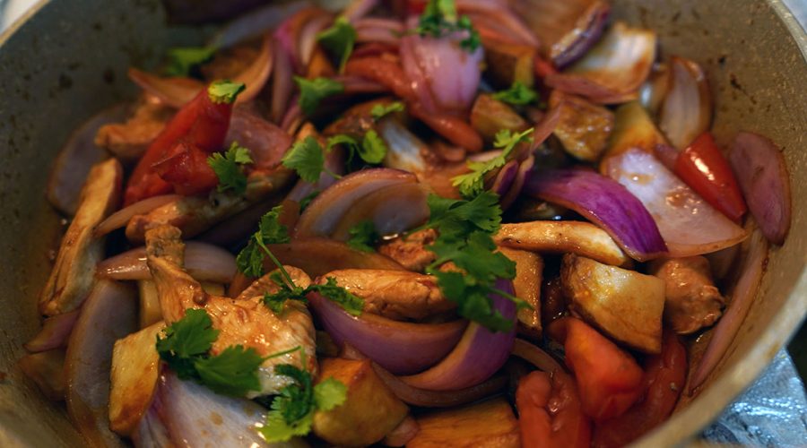 cebolla y ají amarillo salteándose en wok para pollo saltado peruano - onion and aji amarillo stir frying in wok for peruvian chicken saltado