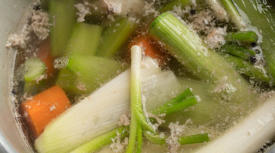 Caldo de gallina hirviendo con verduras en olla - peruvian hen broth boiling with vegetables in pot