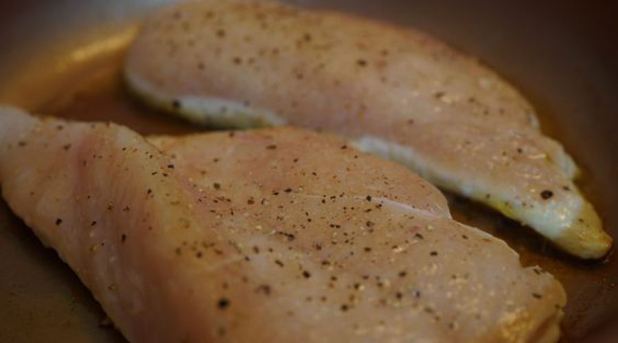 Pechugas de pollo crudas sazonadas con sal y pimienta negra sobre superficie oscura - Raw chicken pieces seasoned with salt and black pepper ready to sear for arroz con pollo